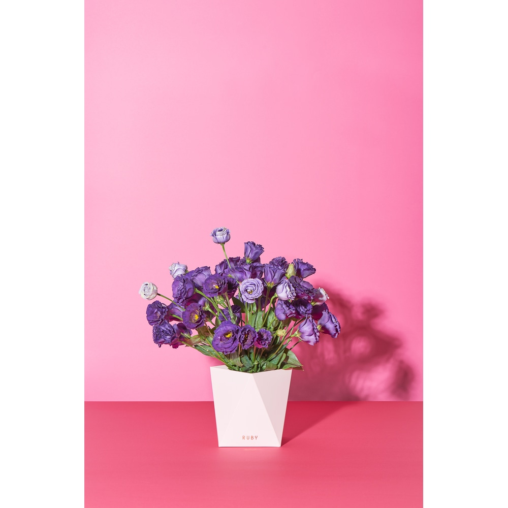 Weisse Ruby Papiervase mit Blumenstrauss vor pinkem Hintergrund.