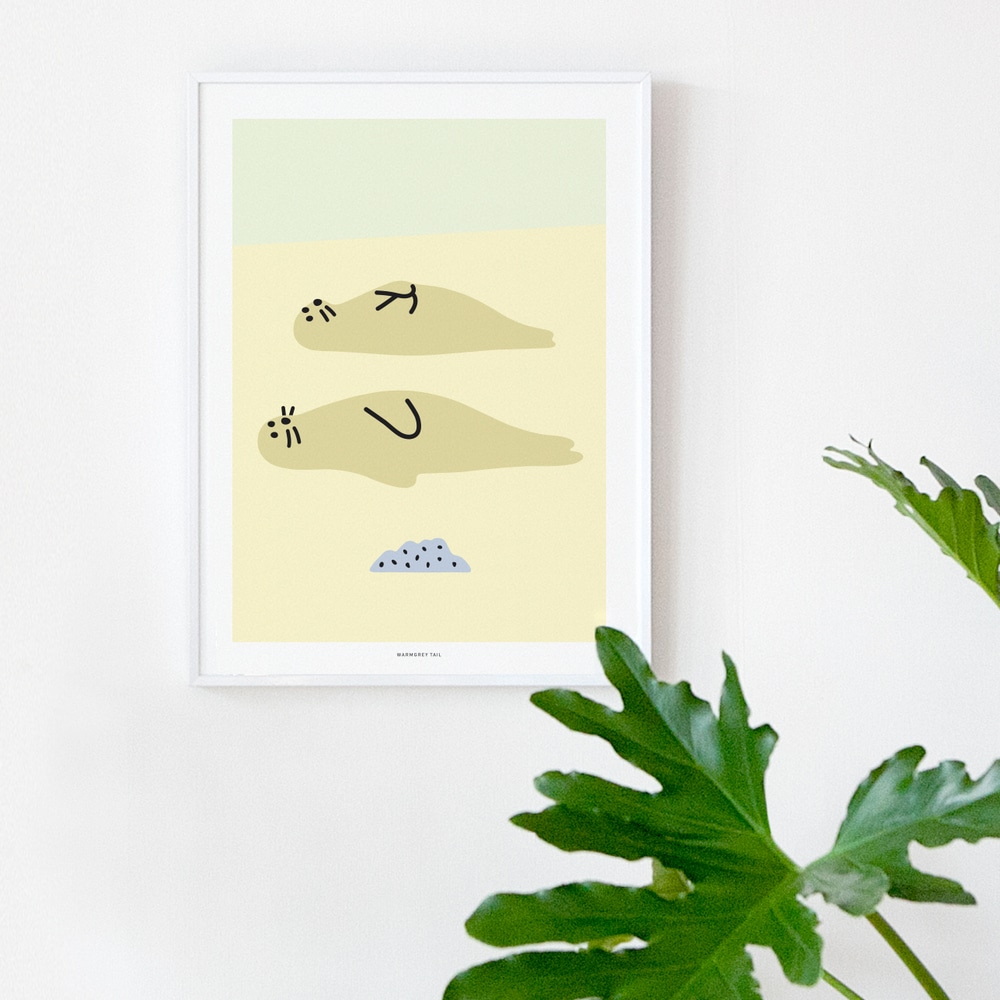 Weiss gerahmter Sealfriends Kunstdruck an weisser Wand neben Gruenpflanzen.