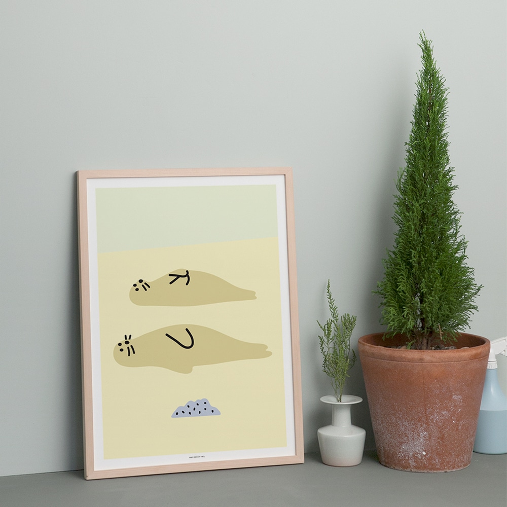 Sealfriends Kunstdruck im Holzrahmen, auf dem Boden vor einer grauen Wand stehend, neben zwei Gruenpflanzen im Tontopf.