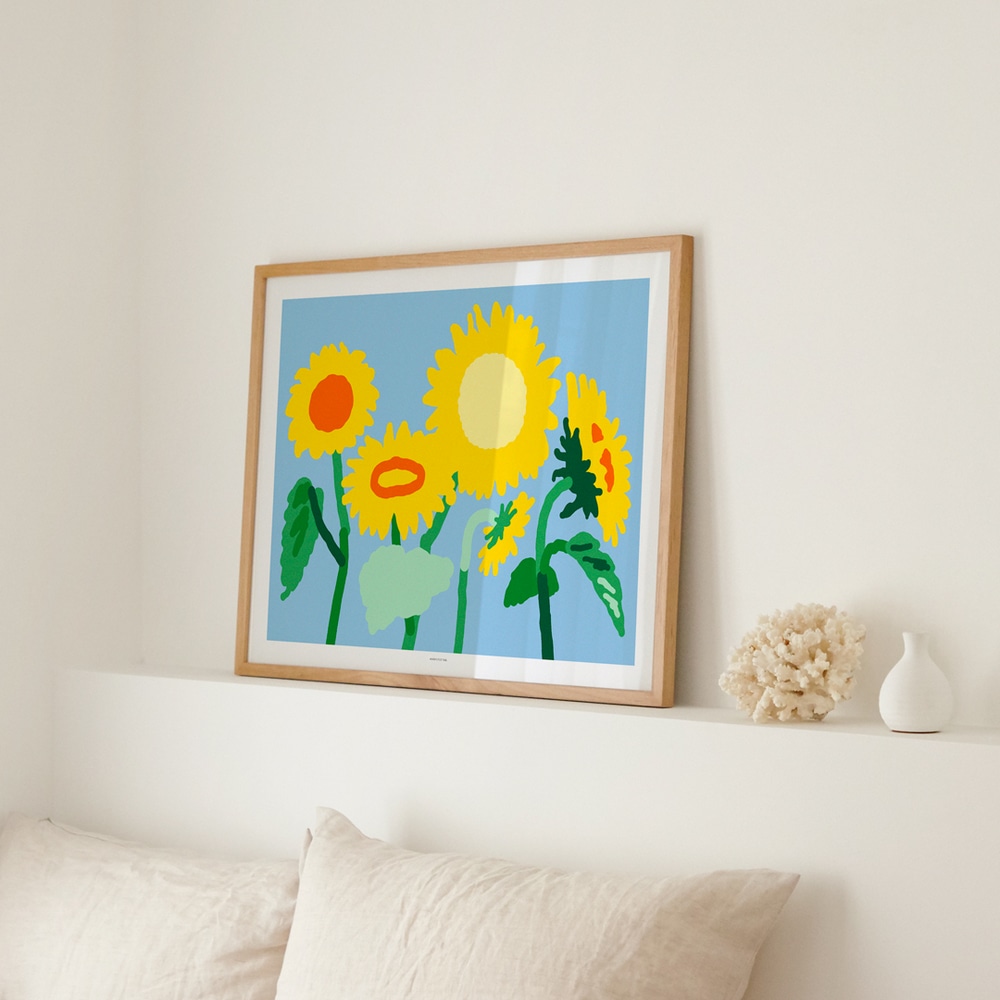 Art Print Sunflower, Sonnenblumen mit gruenen Stengeln und gelben Blueten auf blauem Hintergrund, auf Ablage ueber zwei Bettkissen in weissem Schlafzimmer.