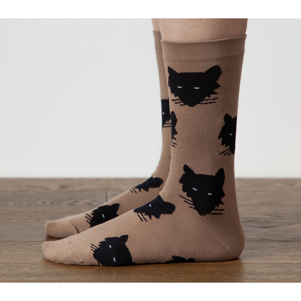 Fuesse in Socken Wolf Beige mit schwarzen Wolfskoepfen, auf Holzboden, von der Seite.