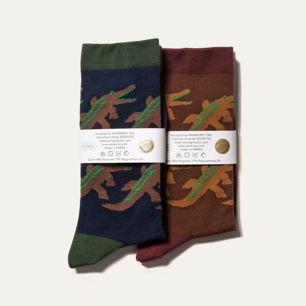 Socken Crocodile in Navy und Brown nebeneinander in Produktverpackung.