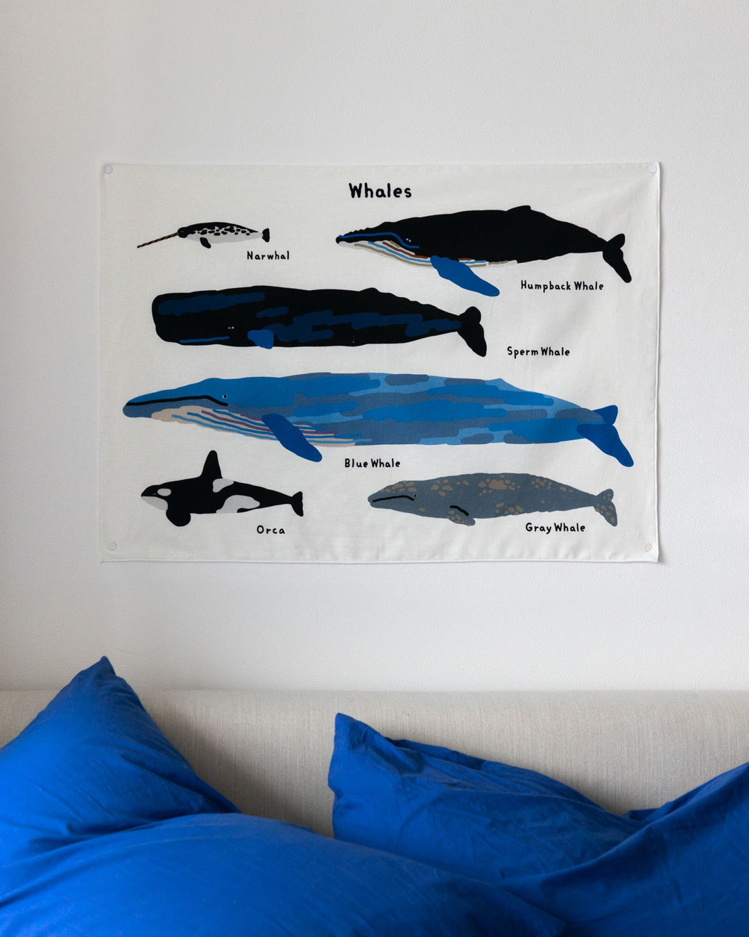Fabric Poster Whales mit verschiedenen Walarten, ueber einem Bett mit blauer Bettwaesche.