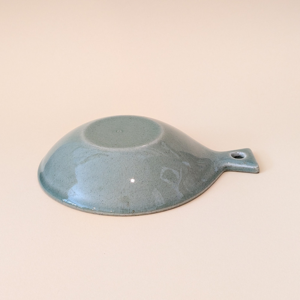 Glasierte Rueckseite des Sonjabi Fish Plate Small, eine kreisrunde Schale in Form eines Fisches, mit Handgriff in Gruen.